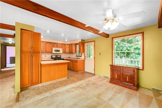a open kitchen with stainless steel appliances granite countertop a refrigerator a stove a sink dishwasher and wooden cabinets with large windows