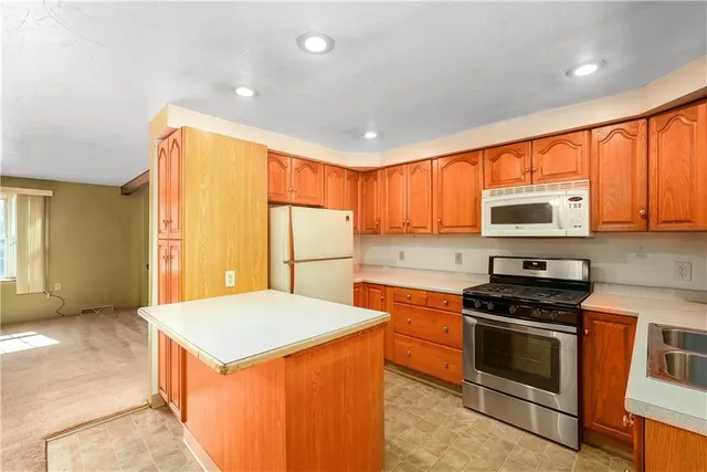 a kitchen with stainless steel appliances a stove top oven a sink a refrigerator white cabinets and wooden floor