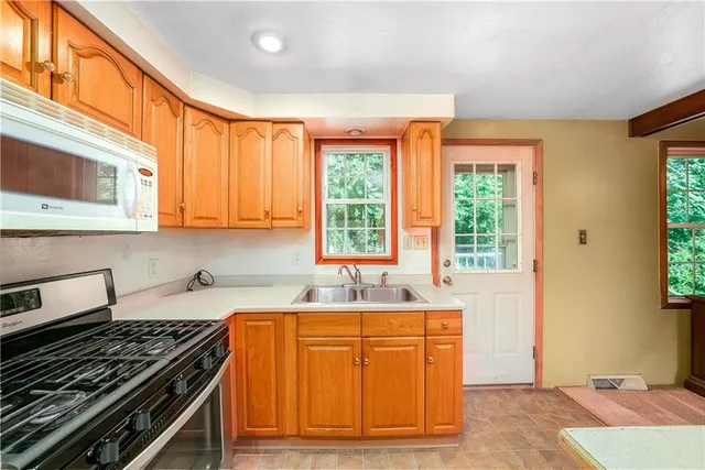 a kitchen with granite countertop a stove a sink and a microwave