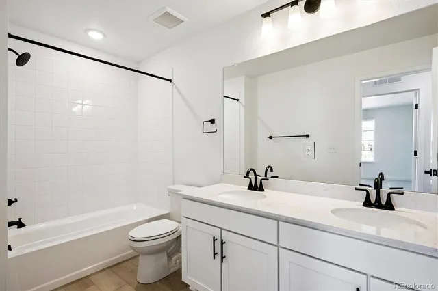 a bathroom with a double vanity sink toilet and shower