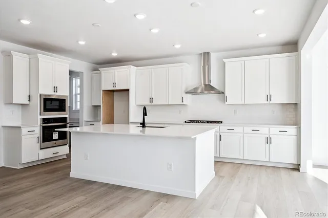a large kitchen with stainless steel appliances granite countertop a stove a sink and white cabinets