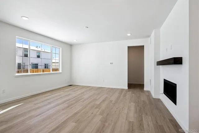 an empty room with windows and fireplace