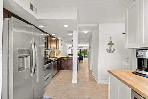 a kitchen with stainless steel appliances kitchen island granite countertop a refrigerator and a stove top oven