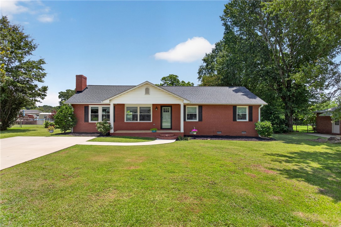A well-maintained brick residence offers a welcoming facade with mature trees and a neatly manicured lawn.