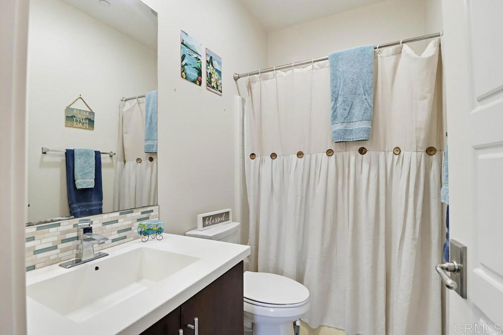 2182 Cosmo Way San Marcos, CA 92078 - Photo 27 of 34 a bathroom with a sink a toilet a mirror and shower curtain