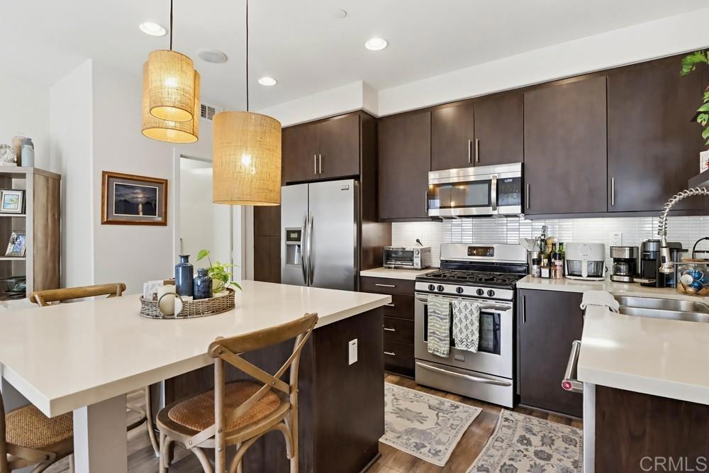 2182 Cosmo Way San Marcos, CA 92078 - Photo 5 of 34 a kitchen with stainless steel appliances a table chairs refrigerator and stove