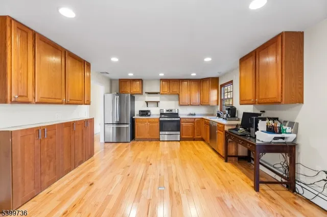 a kitchen with stainless steel appliances wooden floors wooden cabinets a refrigerator and a sink