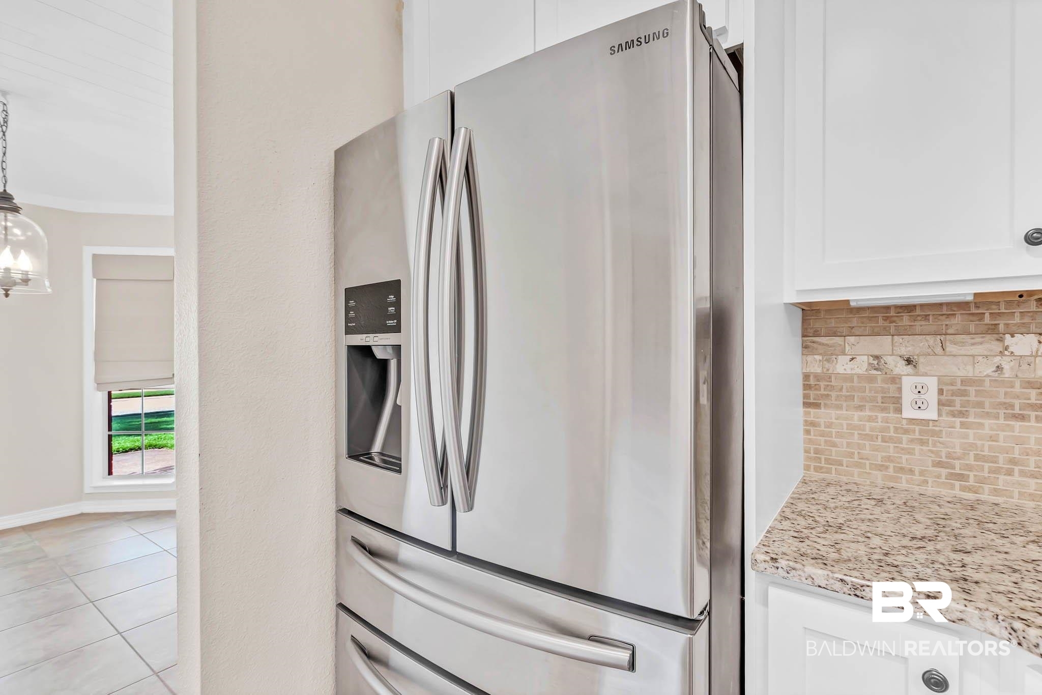 9607 Czar Court Fairhope, AL 36532 - Photo 15 of 42 Kitchen featuring stainless steel refrigerator with ice dispenser, white cabinetry, light stone counters, crown molding, and light tile patterned floors