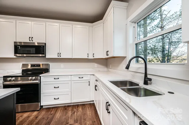 a kitchen with granite countertop a sink and a stove top oven with wooden floors
