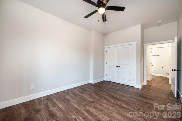 an empty room with wooden floor and ceiling fan
