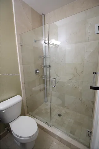 a white toilet next to a bathroom shower