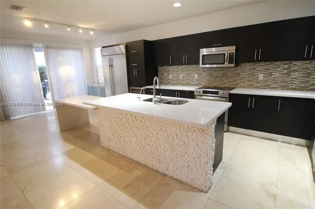 a kitchen with kitchen island stainless steel appliances a sink stove and refrigerator