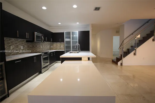 a large room with stainless steel appliances kitchen island a stove and a sink