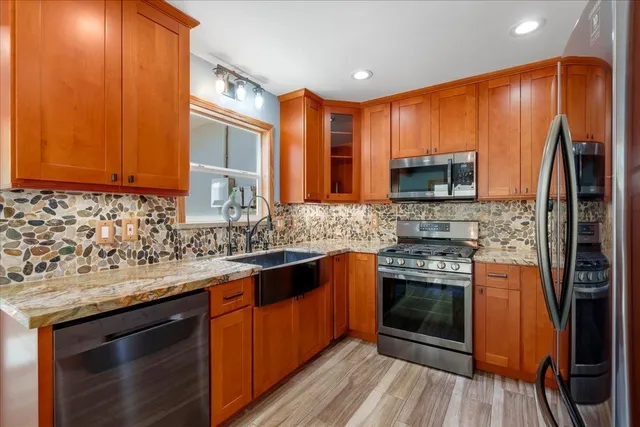 a kitchen with stainless steel appliances granite countertop wooden cabinets a stove top oven a sink and dishwasher
