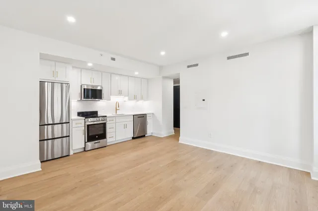a kitchen with refrigerator a microwave and white cabinets
