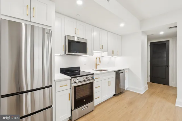 a kitchen with stainless steel appliances a stove a sink and a refrigerator