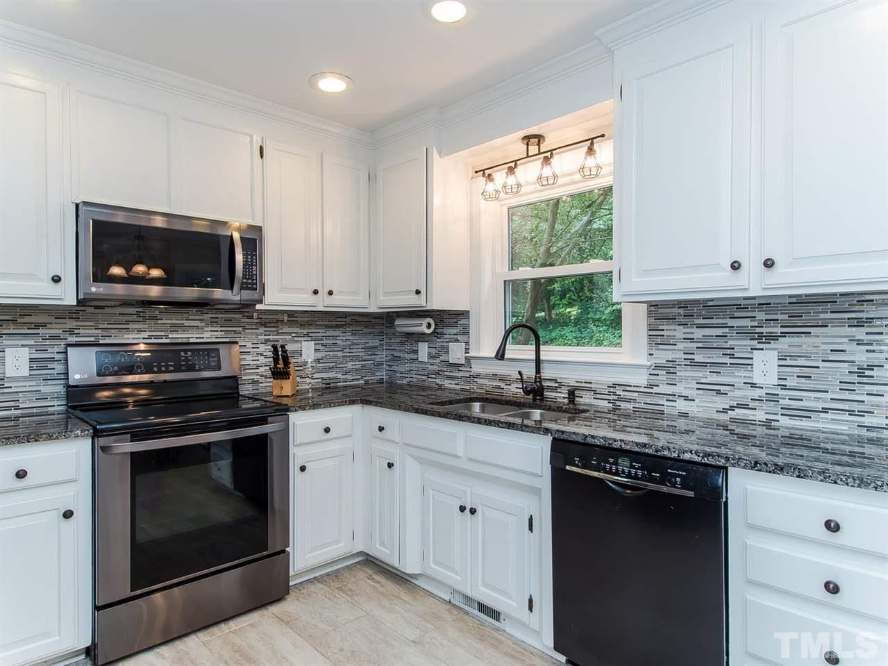 5105 Carter Street Raleigh, NC 27612 - Photo 8 of 25 a kitchen with granite countertop white cabinets appliances a window and a sink