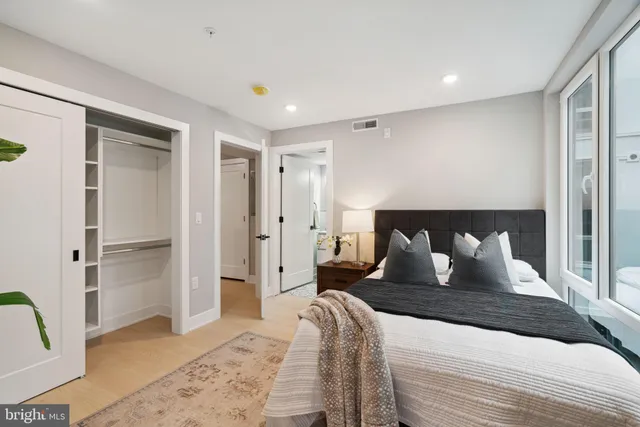 a bed sitting in a spacious bedroom next to a window and a chair