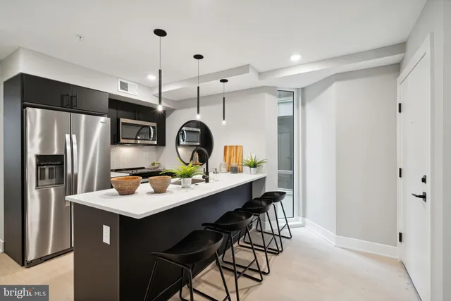 a kitchen with stainless steel appliances a table chairs and refrigerator