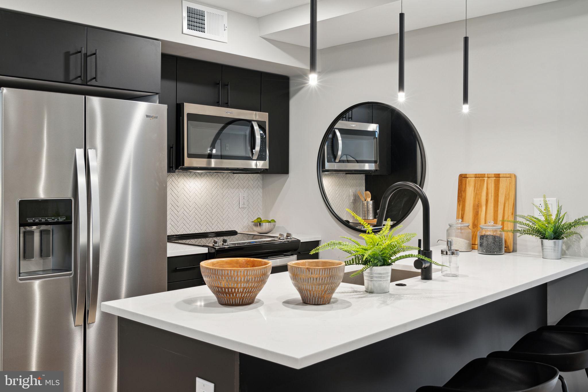 6604 Ridge Avenue, Unit 311 Philadelphia, PA 19128 - Photo 9 of 32 a kitchen with a refrigerator a stove a sink and a dining table