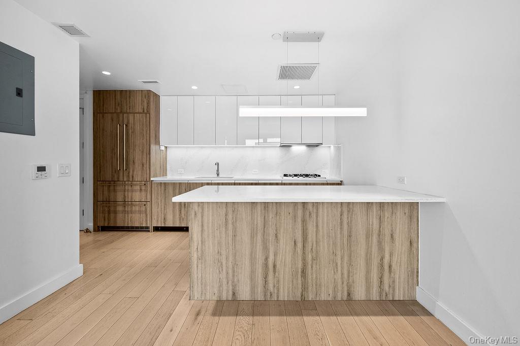 136-18 Maple Avenue, Unit 9A Queens, NY 11355 - Photo 11 of 35 Kitchen with a peninsula, electric panel, light wood-style flooring, modern cabinets, and dual tone cabinets