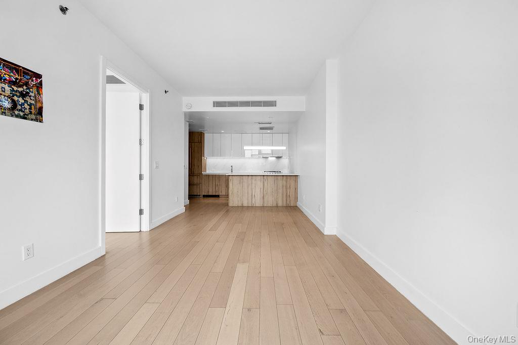 136-18 Maple Avenue, Unit 9A Queens, NY 11355 - Photo 12 of 35 Unfurnished living room with light wood-style floors and baseboards