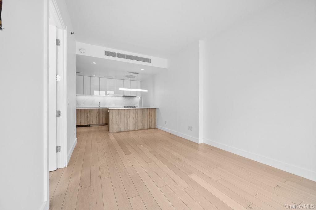 136-18 Maple Avenue, Unit 9A Queens, NY 11355 - Photo 13 of 35 Unfurnished living room with baseboards and light wood finished floors