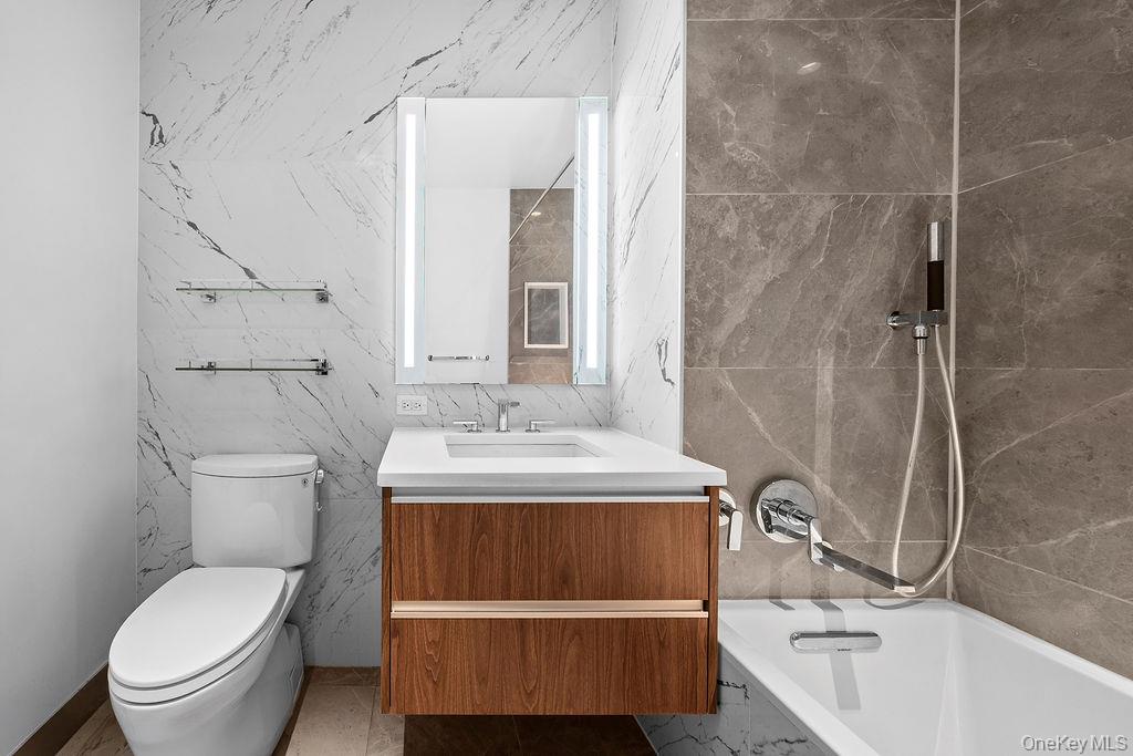 136-18 Maple Avenue, Unit 9A Queens, NY 11355 - Photo 19 of 35 Full bath with vanity, tile walls, and a combined bath / shower with marble appearance