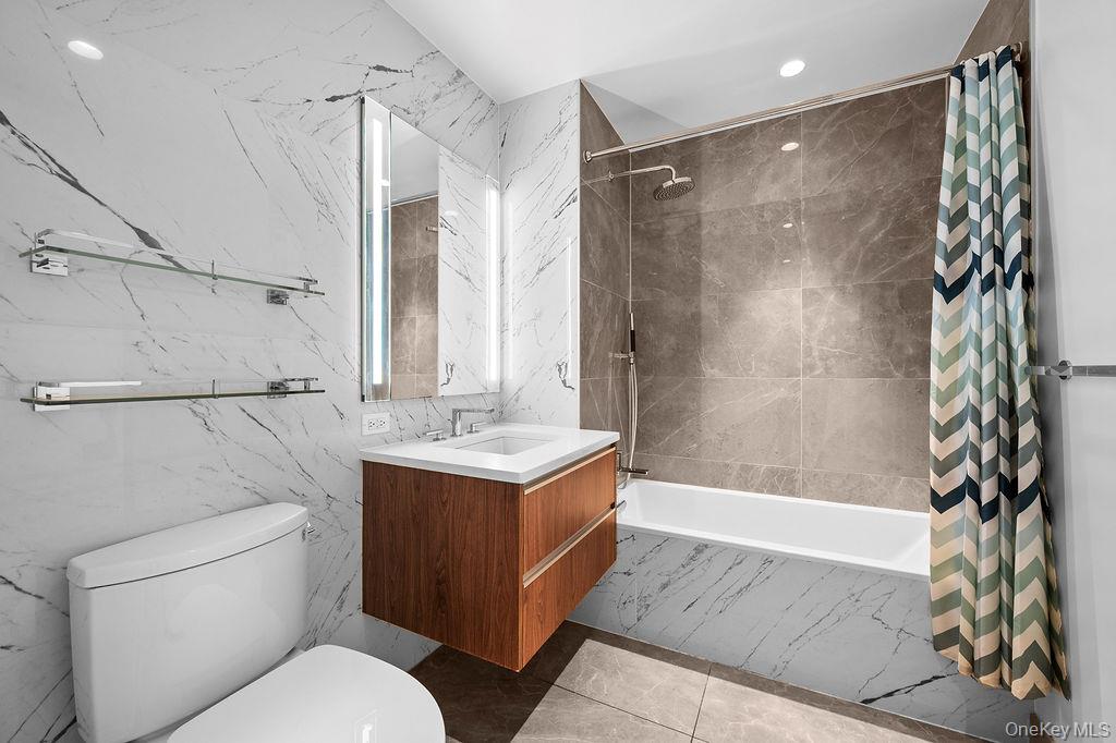 136-18 Maple Avenue, Unit 9A Queens, NY 11355 - Photo 20 of 35 Bathroom with tile walls, vanity, tiled shower / bath combo, light tile patterned flooring, and recessed lighting
