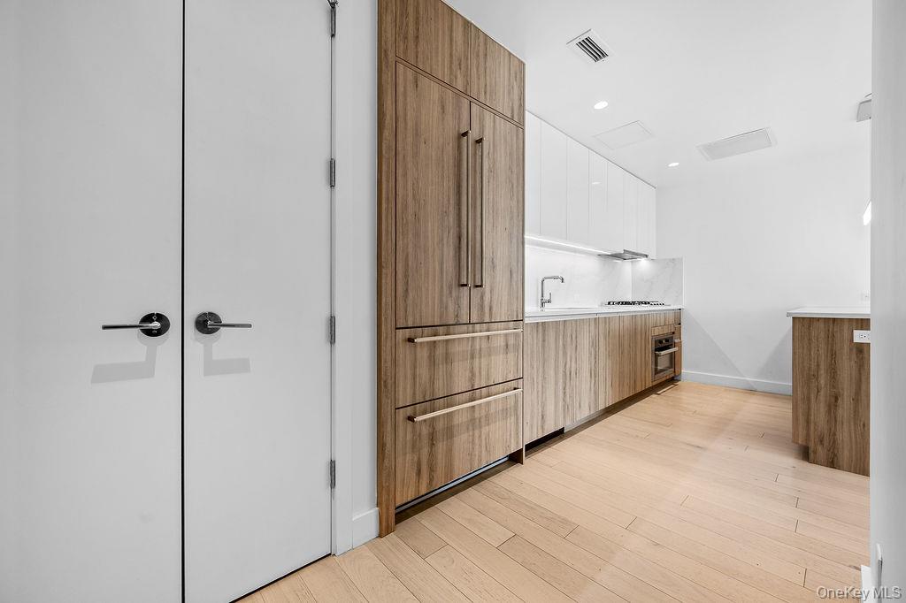 136-18 Maple Avenue, Unit 9A Queens, NY 11355 - Photo 4 of 35 Bar featuring modern cabinets, dual tone cabinets, light wood-style flooring, recessed lighting, and stainless steel oven