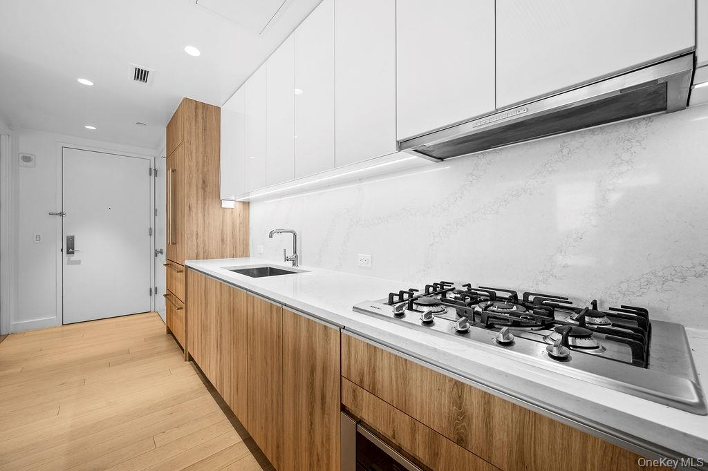 136-18 Maple Avenue, Unit 9A Queens, NY 11355 - Photo 7 of 35 Kitchen featuring modern cabinets, stainless steel gas cooktop, light wood-style floors, dual tone cabinets, and recessed lighting