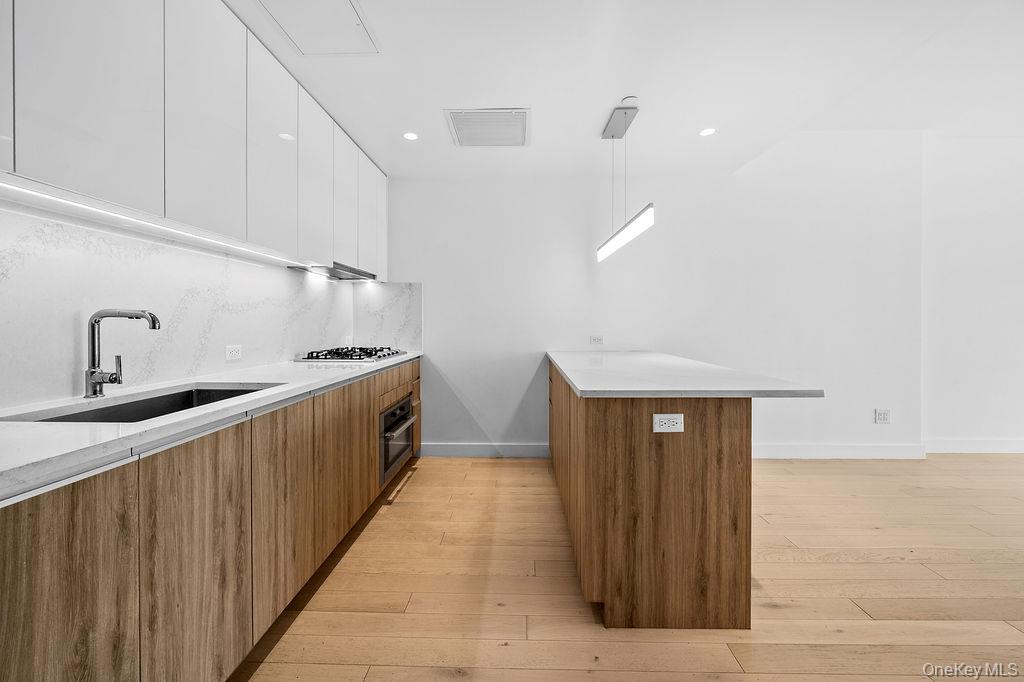136-18 Maple Avenue, Unit 9A Queens, NY 11355 - Photo 8 of 35 Dual tone kitchen with modern cabinets, a peninsula, light stone countertops, and two tone color scheme