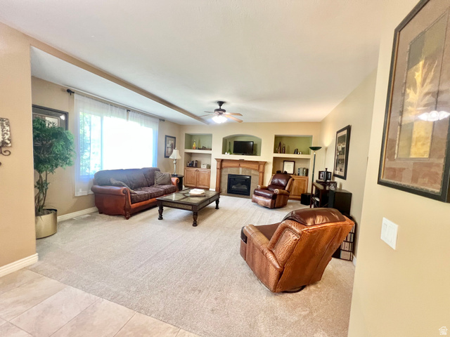 369 Culross Circle Tooele, UT 84074 - Photo 16 of 54 Carpeted living area featuring a built-in fireplace with a wood mantel, recessed shelving, and a large window with sheer treatments