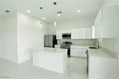 a kitchen with stainless steel appliances a refrigerator sink and white cabinets