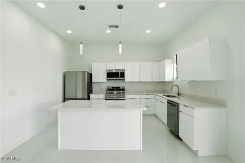 a kitchen with stainless steel appliances a refrigerator a sink a stove top oven and a refrigerator