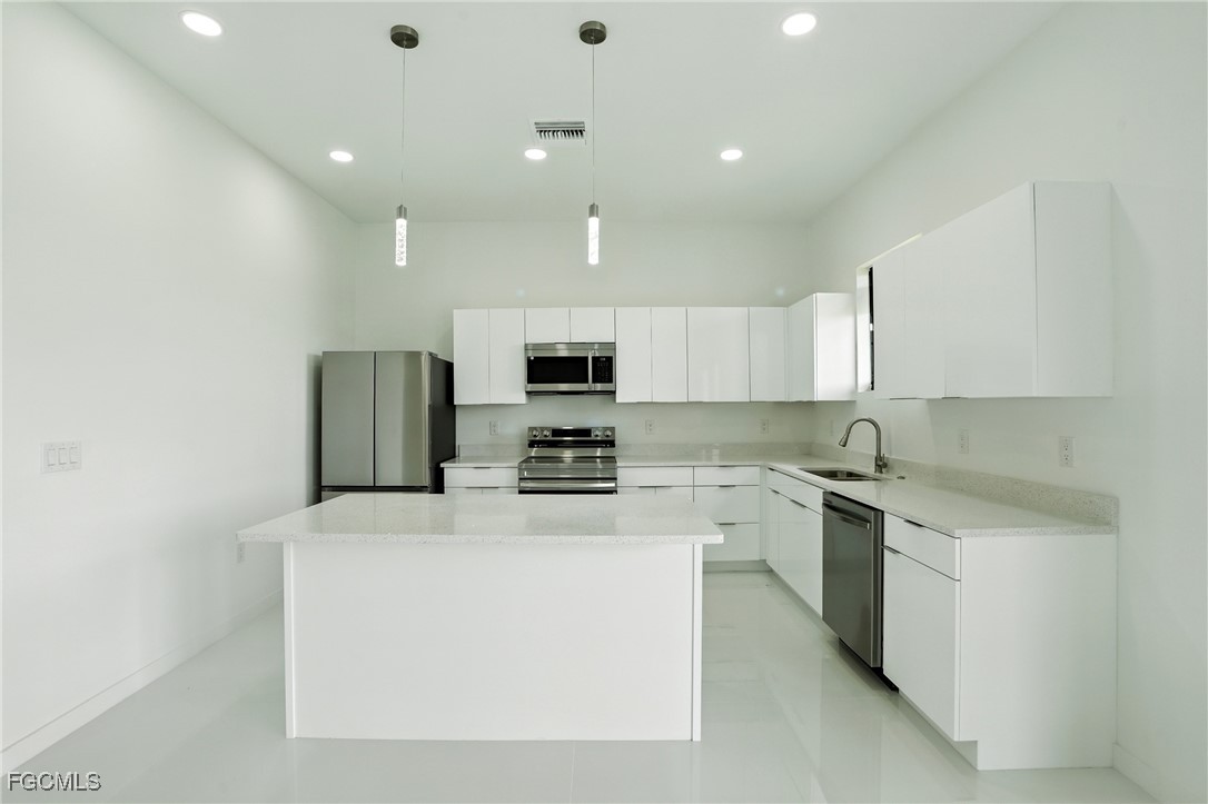 2725 Embers Parkway West Cape Coral, FL 33993 - Photo 10 of 32 a kitchen with stainless steel appliances a refrigerator sink and white cabinets