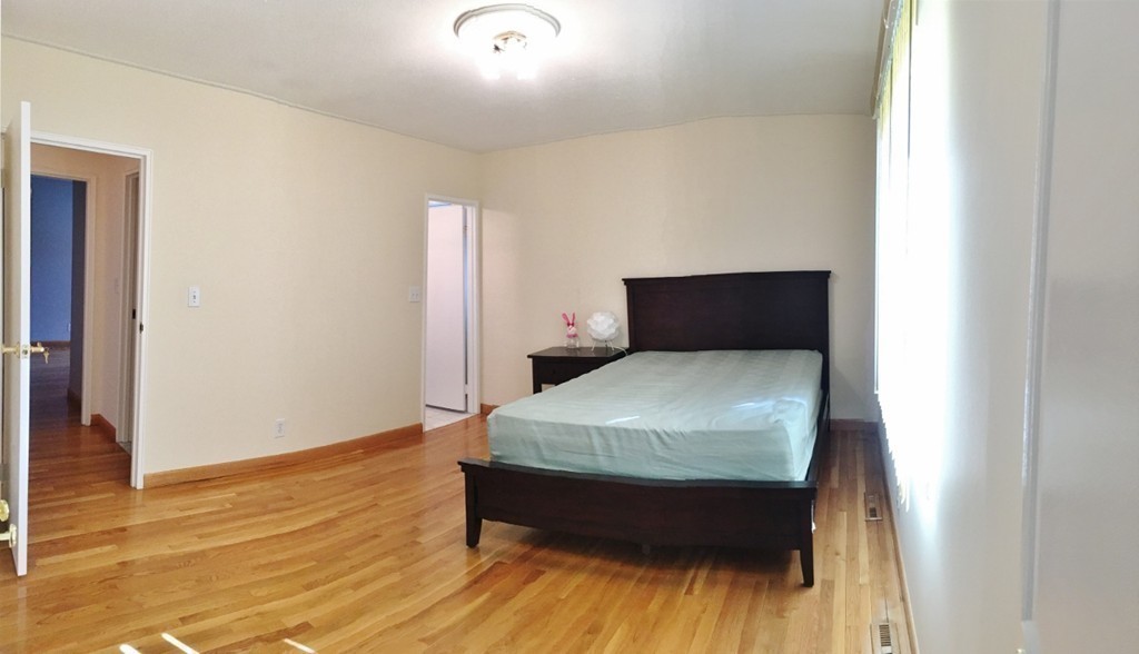 157 Lake Shore Road, Unit 2 Boston, MA 02135 - Photo 24 of 28 a bed sitting in a bedroom next to a window with wooden floor
