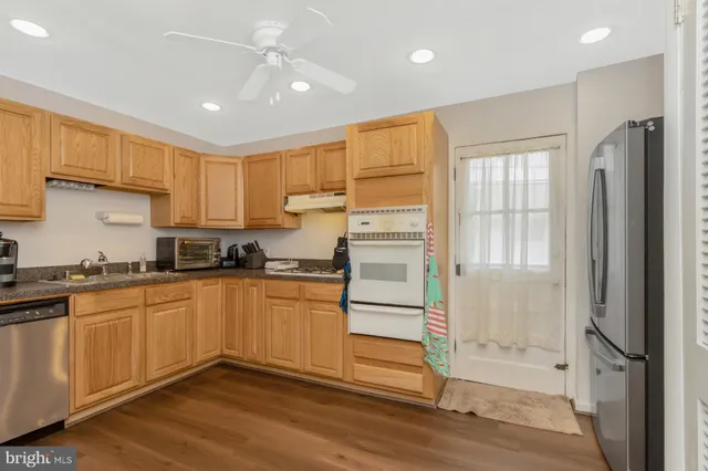 a living room with stainless steel appliances furniture refrigerator and a window