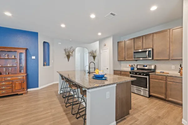 a kitchen with stainless steel appliances granite countertop a stove top oven a sink dishwasher a dining table and chairs with wooden floor