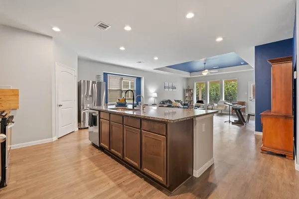 a large kitchen with stainless steel appliances granite countertop a large counter top a sink and a refrigerator