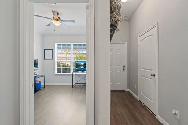a view of an empty room with a window and wooden floor