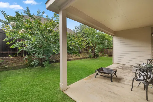 a view of a chair and table in backyard of the house