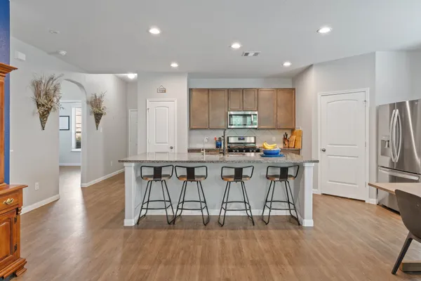 a kitchen with stainless steel appliances a dining table chairs stove and refrigerator