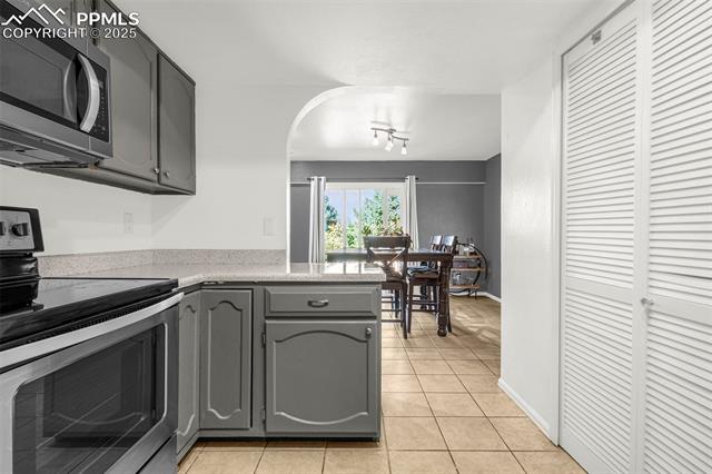 4990 Castledown Road Colorado Springs, CO 80917 - Photo 10 of 37 Kitchen with gray cabinets, a peninsula, stainless steel appliances, and light tile patterned floors