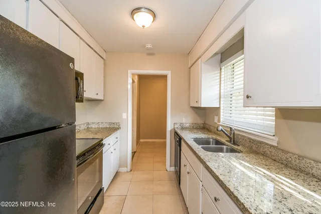 a kitchen with granite countertop a sink stove and refrigerator