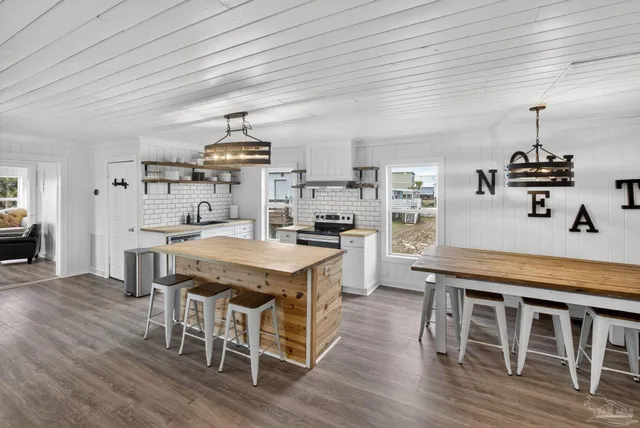 a kitchen with stainless steel appliances granite countertop a table chairs stove and wooden floor