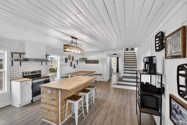 a kitchen with stainless steel appliances granite countertop a stove top oven a sink dishwasher and white cabinets with wooden floor