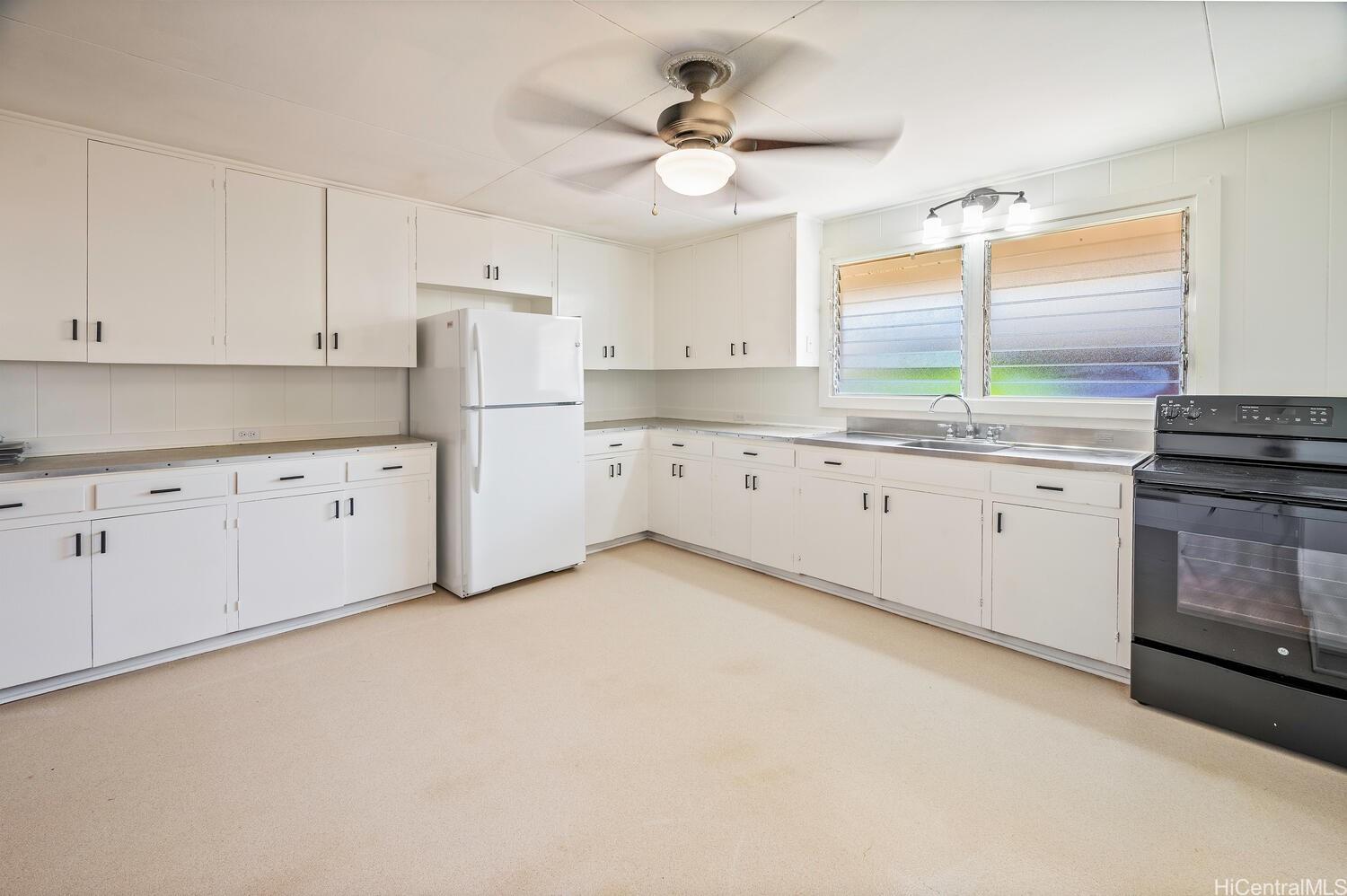 930 16th Avenue Honolulu, HI 96816 - Photo 10 of 24 a kitchen with granite countertop a sink a stove a refrigerator and white cabinets