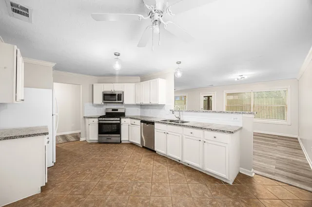 a large kitchen with granite countertop a stove top oven a sink a counter space and cabinets