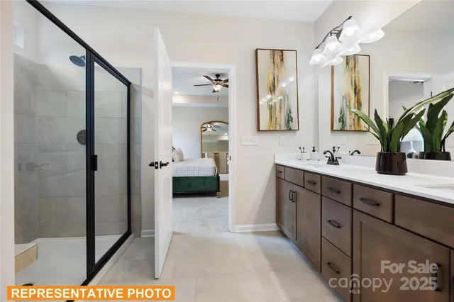 a en suite bathroom with a double vanity sink a mirror and shower